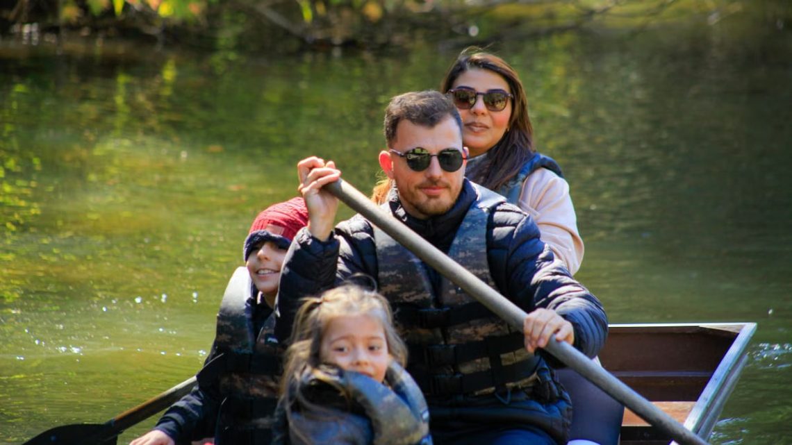 A family of four rowing a canoe on a serene lake during a sunny day, enjoying an outdoor adventure.